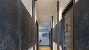 A hallway with dark and light walls, a patterned carpet, and doors on both sides. - Front One Boutique Karawang (Karawang)