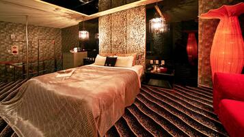 Una habitación de hotel moderna con una cama grande, un sillón rojo y una pared con una textura original.