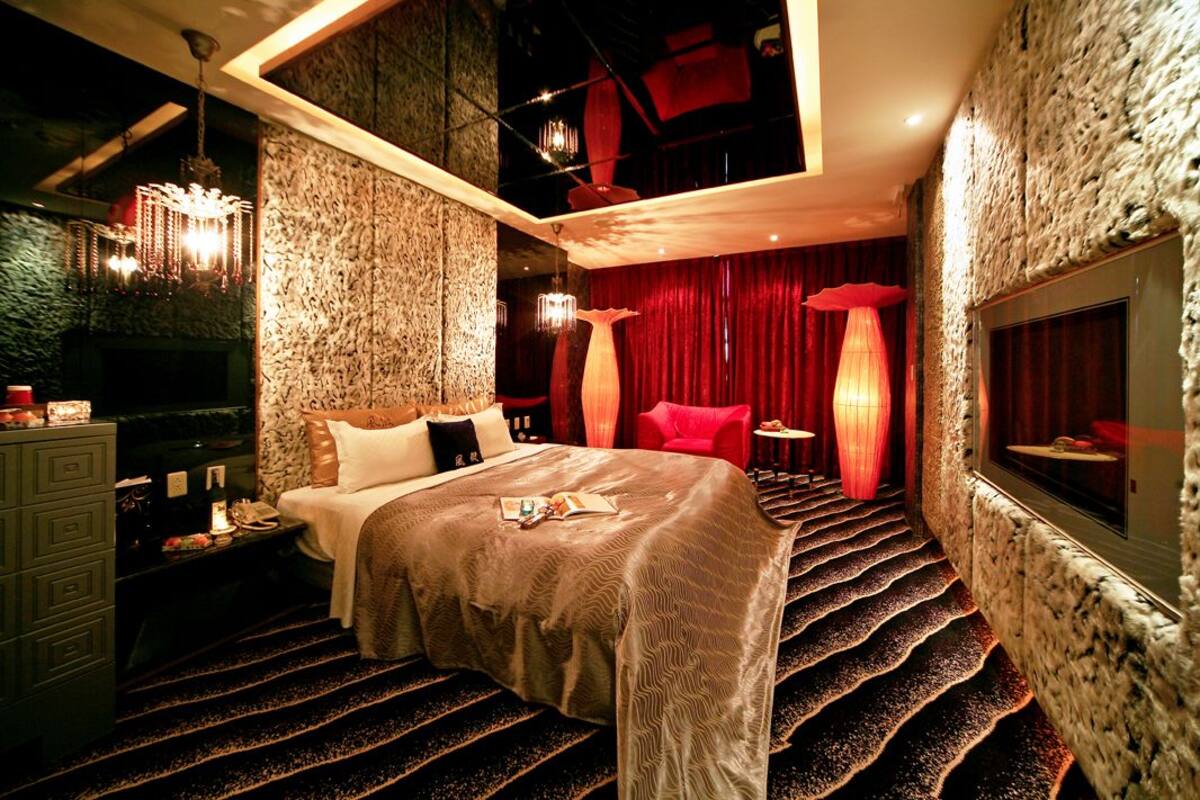 A luxurious bedroom with a large bed, a red chair, and a unique staircase design.