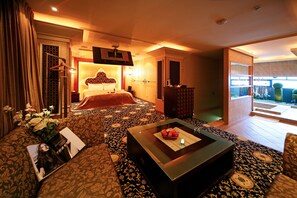 A hotel room with a large bed, a coffee table, a TV, and a balcony with a view. - Fongchin Motel (Taichung)