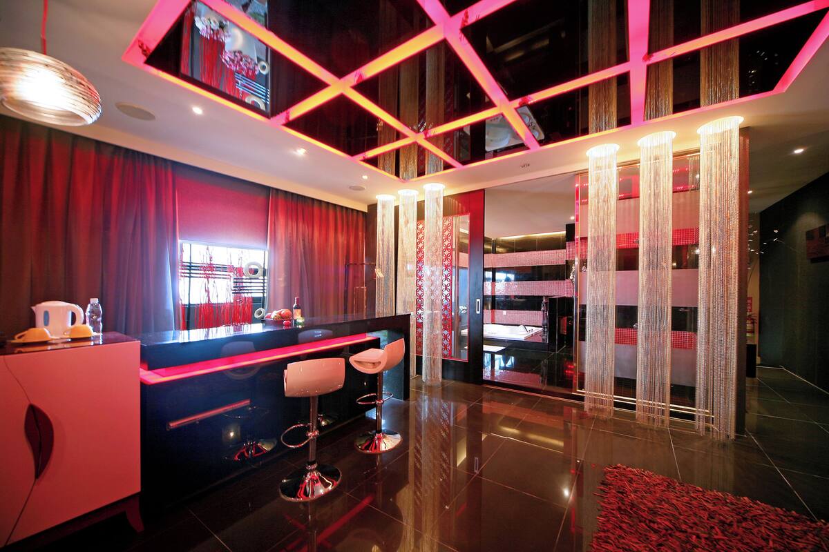 A modern hotel lobby with a bar area, seating, and a large mirror reflecting the interior.