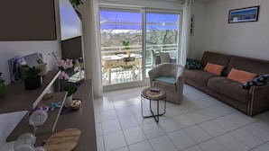 En stue med sofa, rundt sofabord og en balkon med bord og stole.