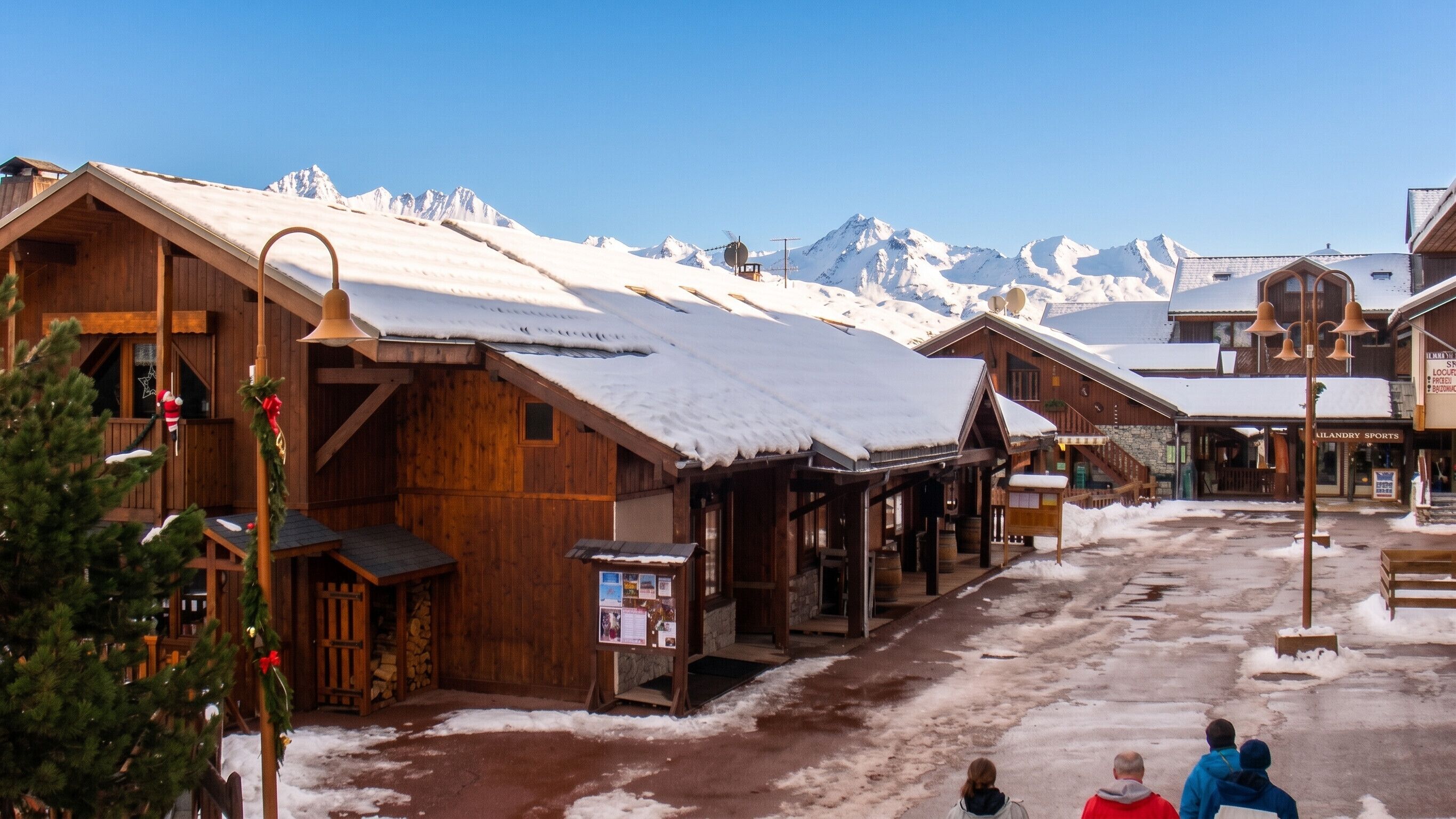 Un bâtiment en bois, doté d’une cloche, d’une enseigne et offrant une vue sur des montagnes enneigées.