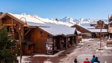 Un bâtiment en bois, doté d’une cloche, d’une enseigne et offrant une vue sur des montagnes enneigées.