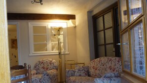 Una sala de estar acogedora con sofás de estampado floral, una silla de madera y una lámpara de pie.