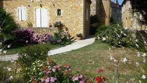 Un edificio de piedra con un jardín delantero, con un camino que lleva a la entrada.
