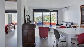 A modern living room with a dining area, a wooden cabinet, and a balcony with a view of the outdoors. - Casa San Ghjisé (Bastia)