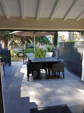 A covered patio with a table and chairs, a pergola, and a view of the surrounding garden. - Studio Seaside at st cyr sur mer (Saint-Cyr-sur-Mer)