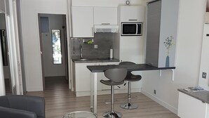 Une cuisine moderne avec des meubles blancs, un four à micro-ondes et un petit coin repas comprenant une table et deux chaises.