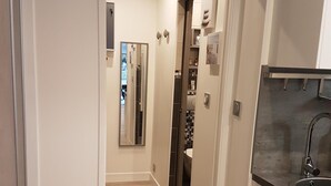 Un couloir étroit, doté d’un plancher en bois, mène à une cuisine équipée d’un évier et de placards.