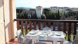 A balcony with a table set for dining, overlooking a town with a church tower and residential buildings.