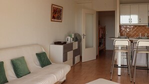 A compact living space with a sofa, a kitchenette, and a dining area.