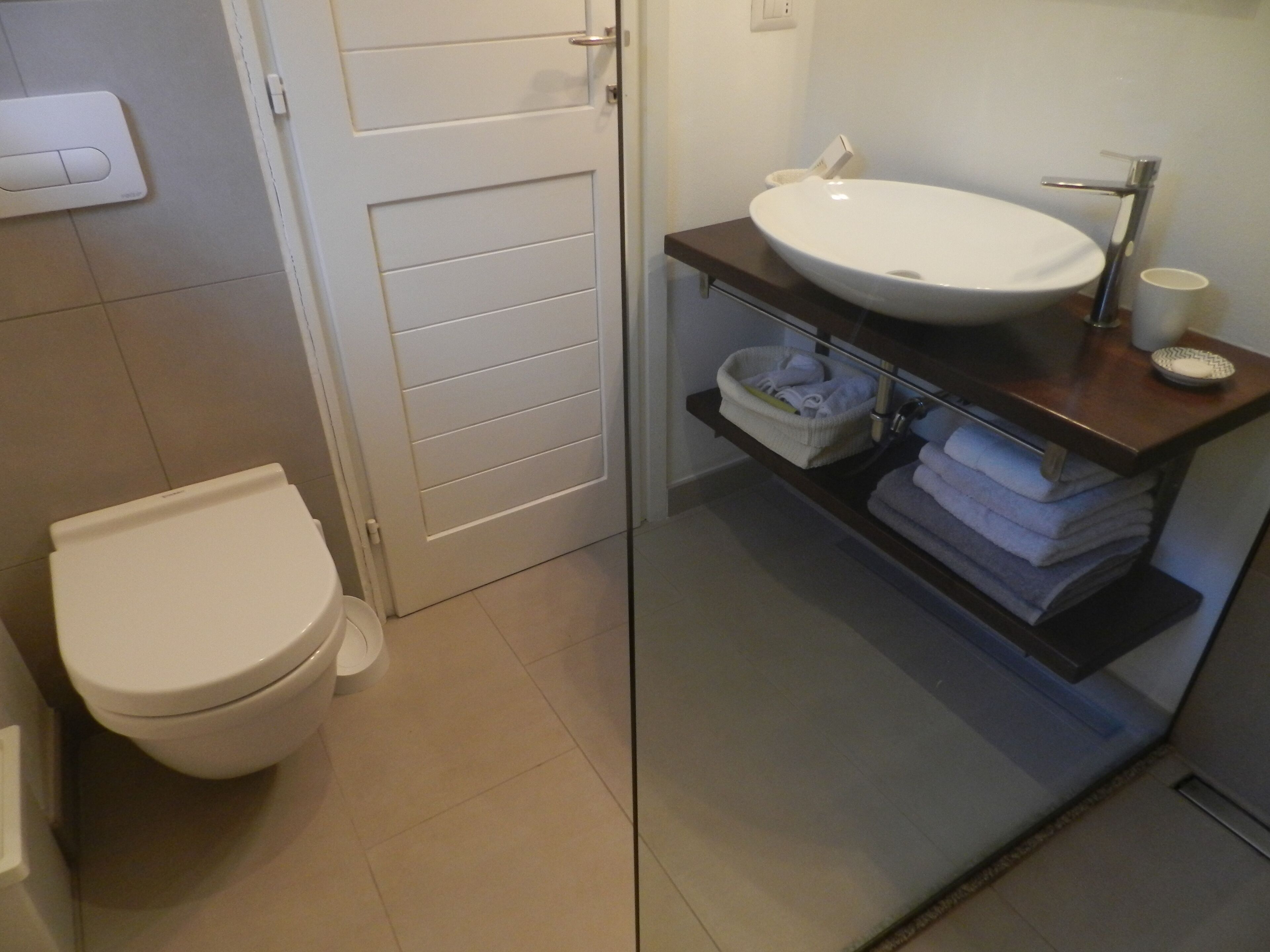 A bathroom with a white toilet, a sink with a mirror, and a towel rack.