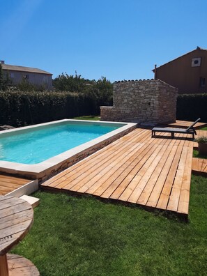 A swimming pool with a wooden deck, a stone wall, and a grassy area. - Homerez - Villa in Saint-Saturnin-lès-Apt (Saint-Saturnin-lès-Apt)