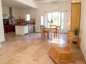 Una cocina amplia con comedor, una silla de mimbre y vistas al exterior.