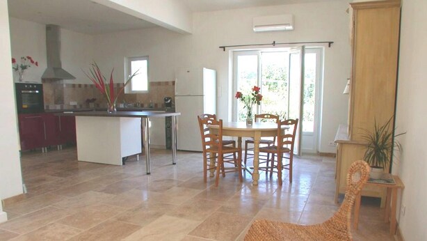 Una cocina amplia con comedor, que cuenta con una isla grande, sillas de madera y una silla tejida.
