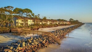A beachfront hotel with multiple-story buildings, a wooden walkway, and a rocky shoreline. - Ocean Cottage 39 Halekulani The Cottages at Jekyll Island Oceanfront (Jekyll Island)