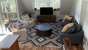 A living room with a TV, sofa, armchair, and coffee table.