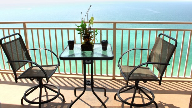A balcony with a table and two chairs, overlooking a body of water. - Splash Luxury Oceanfront Condo with Master on Gulf! (Panama City Beach)
