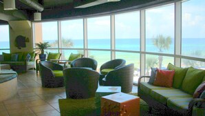 A room with large windows overlooking the ocean, furnished with green and gray chairs and a green sofa. - Splash Luxury Oceanfront Condo with Master on Gulf! (Panama City Beach)