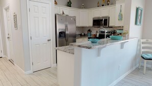 Una cocina moderna con armarios blancos, electrodomésticos de acero inoxidable y encimera de granito.