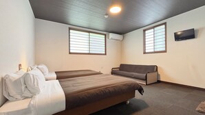 A bedroom with two beds, a sofa, a TV, and an air conditioning unit. - Pension Kobekko (Otari)