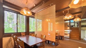 A conference room with a large table, chairs, and hanging pendant lights. - Pension Kobekko (Otari)