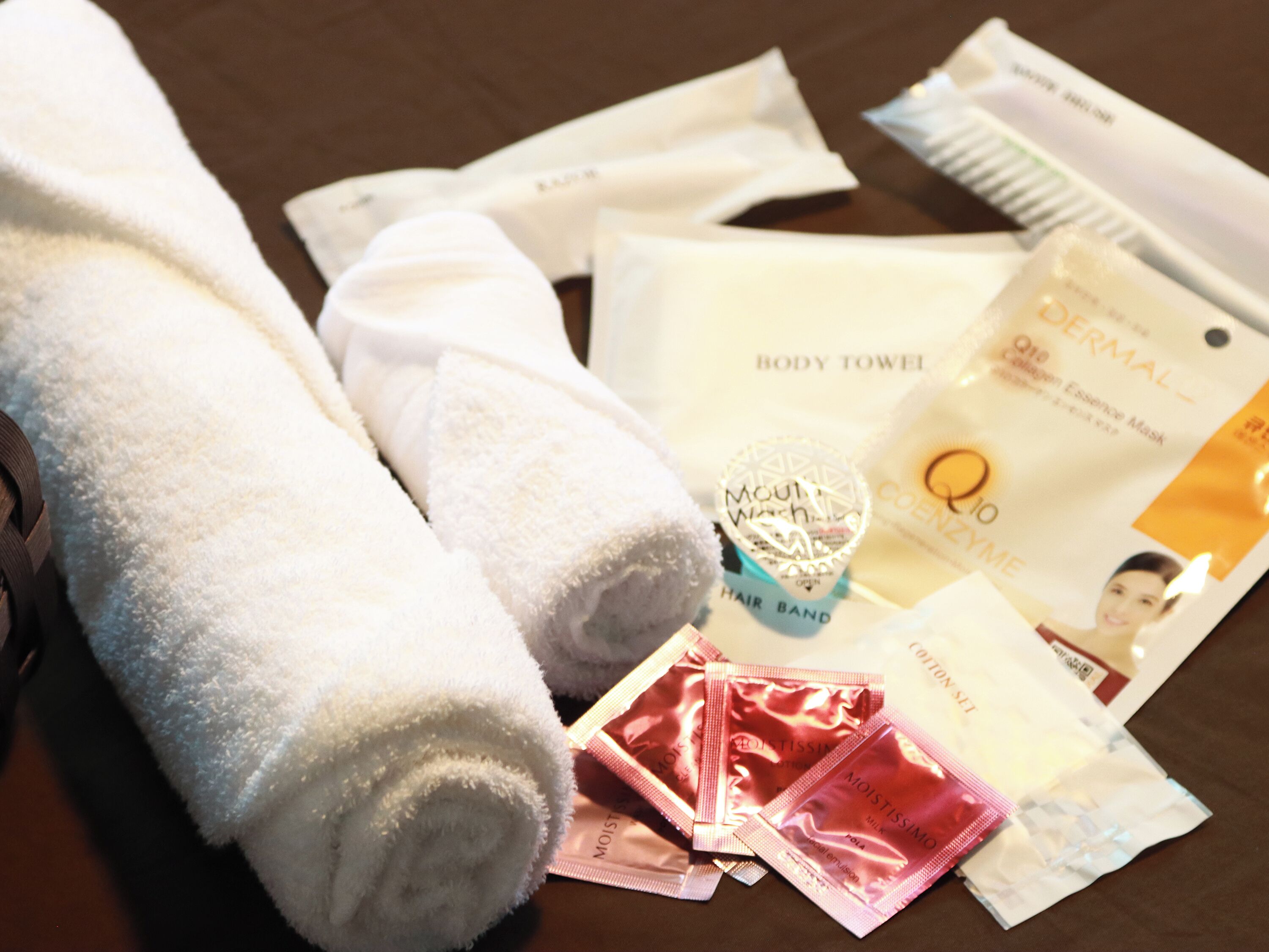 A set of white towels, a hair band, and various personal care items on a wooden surface.