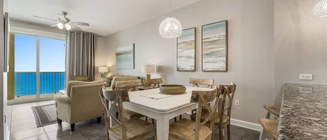 A spacious living area with a dining table, chairs, and a view of the ocean.