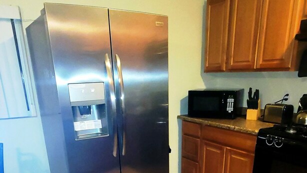 A kitchen with a stainless steel refrigerator, wooden cabinets, a microwave, and a toaster. - 5 STAR ESCAPE - Death Valley - Spring Mountain - Prairie Fire Nevada  (Pahrump)