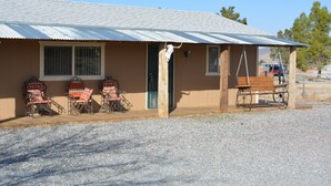 A building with a corrugated metal roof, a wooden door, and a bench outside. - 5 STAR ESCAPE - Death Valley - Spring Mountain - Prairie Fire Nevada  (Pahrump)