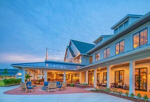 Une maison à deux étages dotée d’un patio couvert, d’un espace salon extérieur et d’une grande baie vitrée.