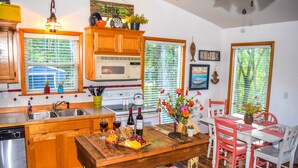 Una cocina con armarios de madera, microondas, lavabo y comedor con mesa y sillas.