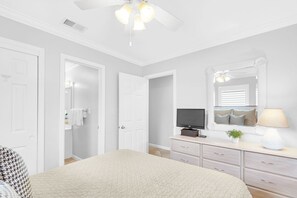 Relax in this serene bedroom with a large bed, TV, dresser, and mirror.