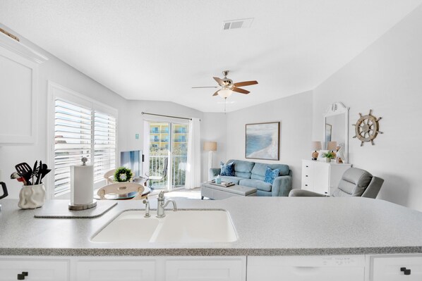A modern kitchen with a large island, white cabinetry, and a view to the living area. - 👣Steps to Private Beach Access-Pool + Hot Tub-1BR Gulfview II 318🌊️ (Miramar Beach)