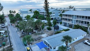 A coastal residential area with multiple two-story houses, a beach view, and a parking area with a few vehicles. - 120 steps to beach!  Safely on the beach side of the road! (Englewood)
