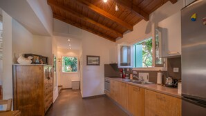 A modern kitchen with wooden cabinets, a stainless steel refrigerator, and a window providing natural light. - My Little House - Family House with Private Terrace (Aegina)
