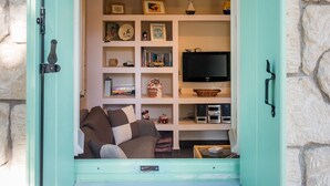 A cozy room with a stone wall, a green door, and a bookshelf filled with books and decorative items. - My Little House - Family House with Private Terrace (Aegina)