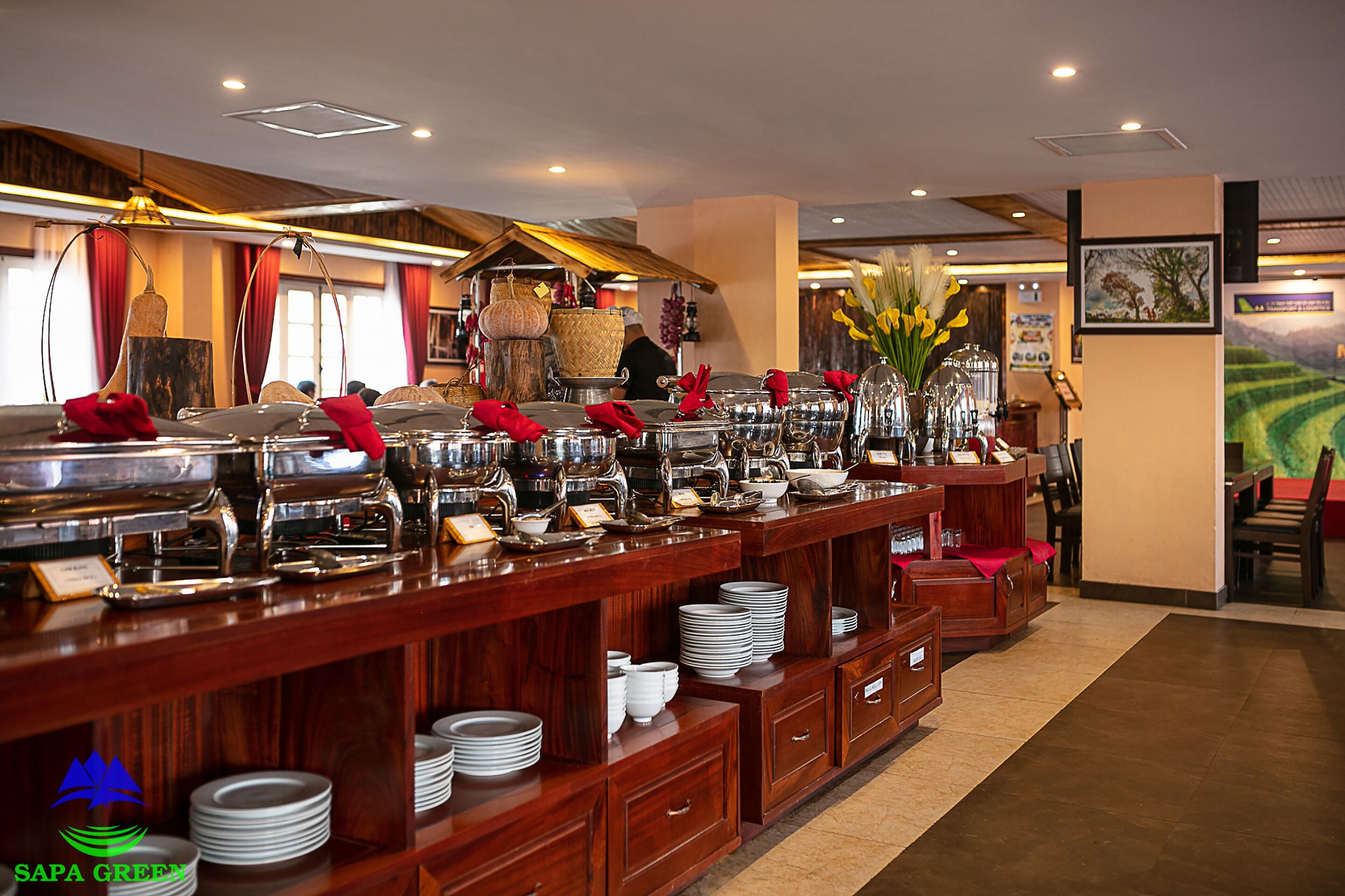 A buffet setup with multiple serving stations, a variety of dishes, and a decorative vase with flowers.