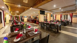 A spacious restaurant with multiple dining tables set for guests, featuring a high ceiling with wooden beams and a modern chandelier. - Sapa Green Hotel (Sa Pa)