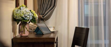 Uma escrivaninha de madeira com um laptop, um vaso de flores e um telefone.