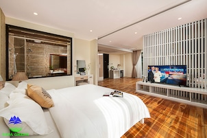 A hotel room with a large bed, a television, a desk, and a bathroom visible through an open door.
