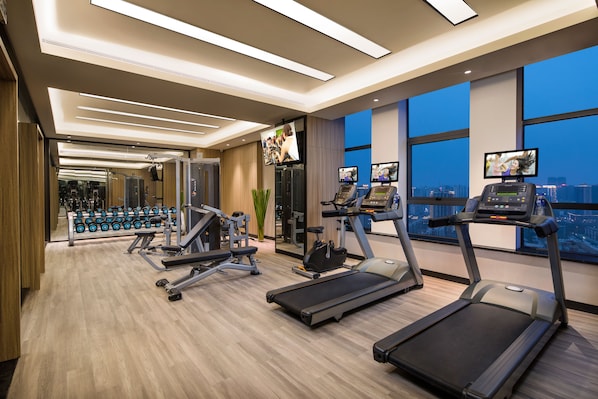 Un gimnasio moderno con cintas de correr, mancuernas y máquinas de pesas.