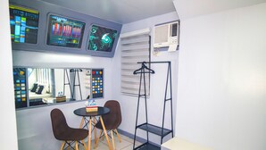 A room with a table and two chairs, a window with a view, a wall-mounted air conditioner, and a wall-mounted control panel. - Astrotel Monumento (Caloocan)