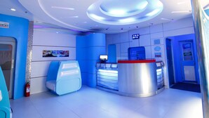 A modern reception area with a blue and white color scheme, a digital display, and a fire extinguisher. - Astrotel Monumento (Caloocan)