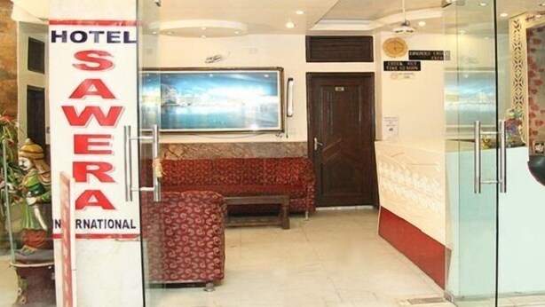Un vestíbulo de hotel con una recepción, una zona de estar y un amplio ventanal.