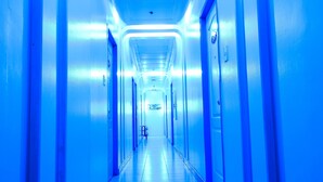 Un pasillo largo y estrecho con puertas a ambos lados, que conduce a una habitación luminosa al final.