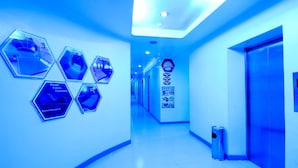 Un pasillo con espejos hexagonales en la pared, un cubo de basura y un ascensor.