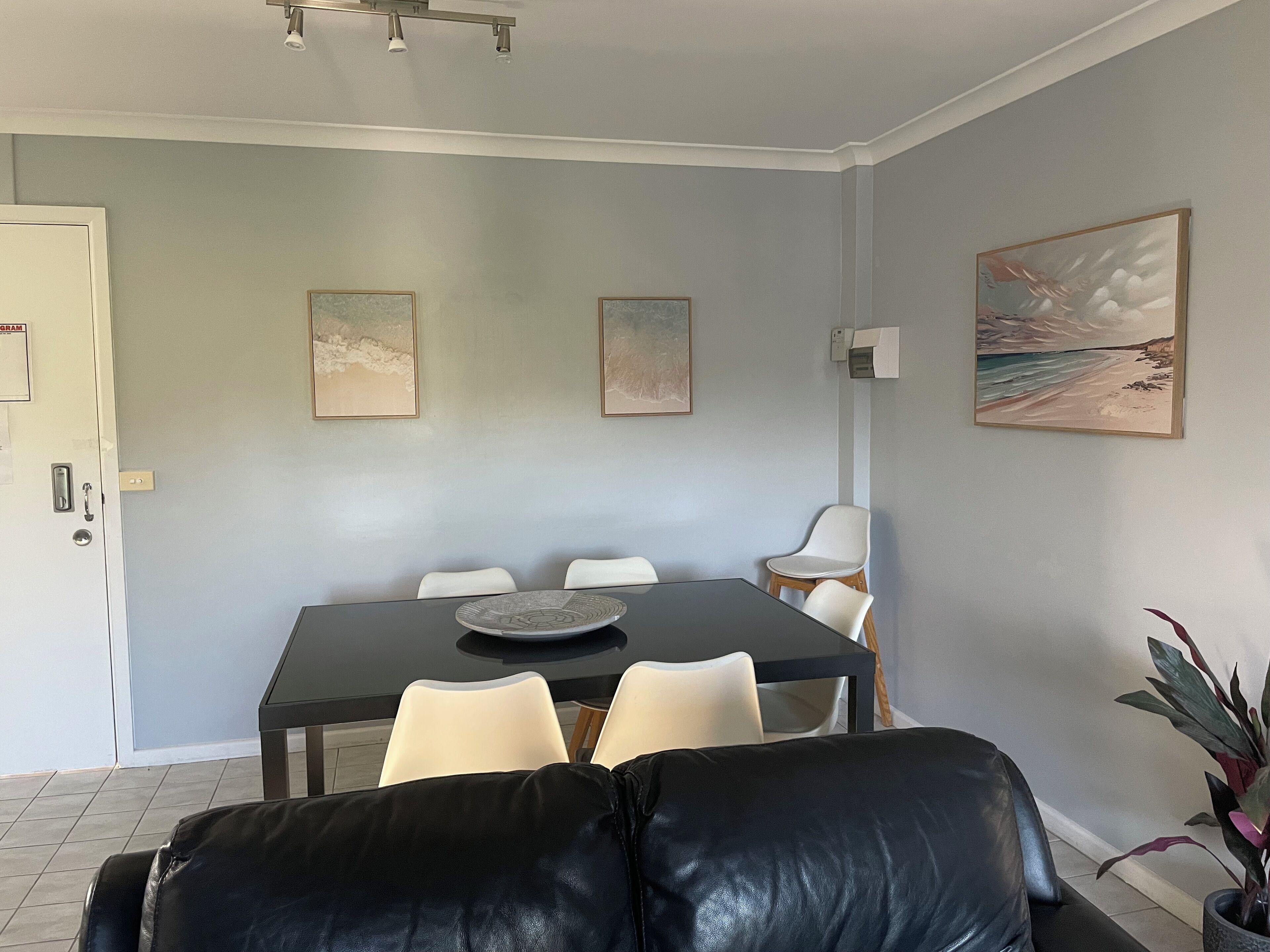 Uma sala de jantar com uma mesa, cadeiras e um quadro na parede.