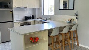 Une cuisine moderne dotée d’un îlot central, de tabourets de bar, d’un four à micro-ondes et d’un réfrigérateur.